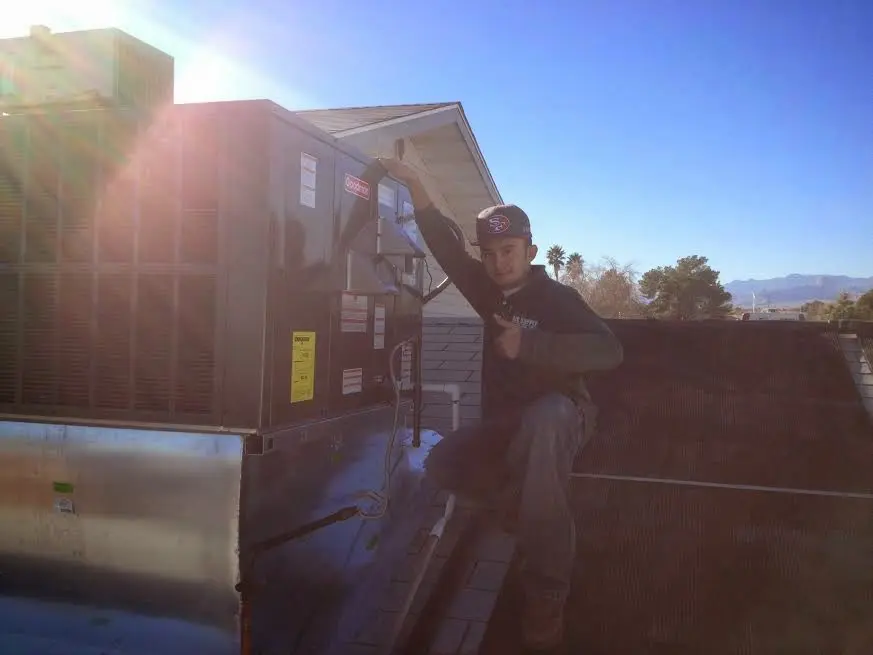 HVAC technician performing AC Tune-Up on a rooftop unit in Dighton
