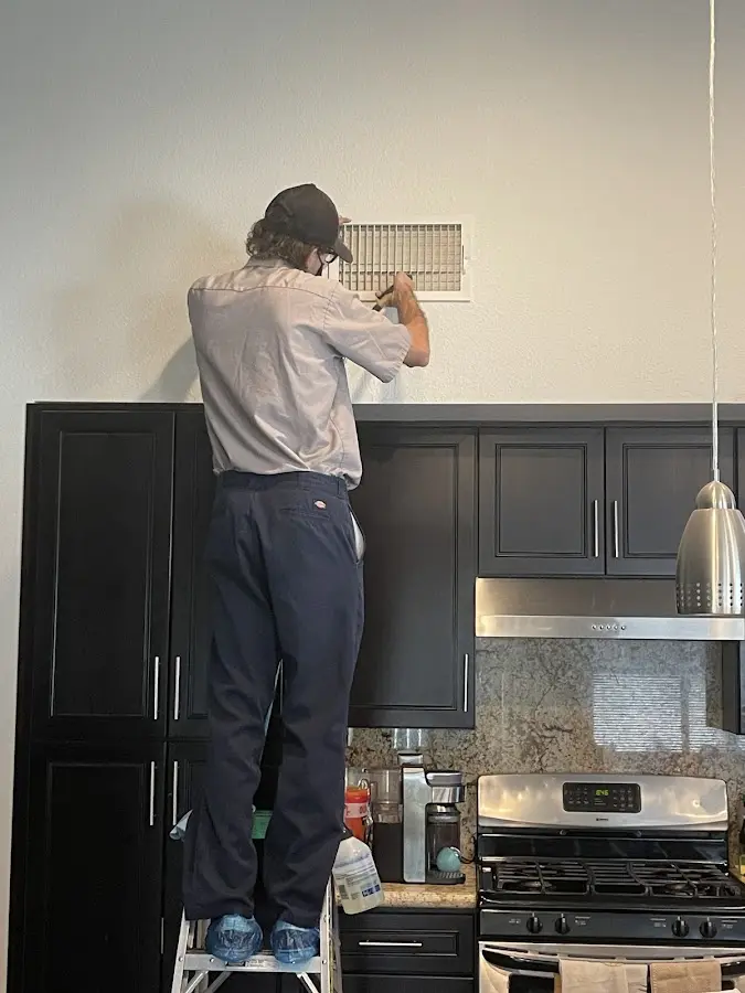 Technician inspecting an air vent during HVAC service in Dighton